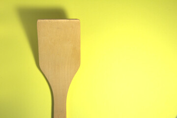 Wooden spatula. On a yellow background. In the close-up.
