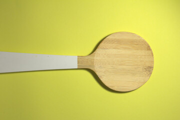 Wooden large spoon. On a yellow background.