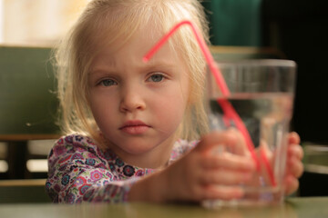 Portrait of a sweet beautiful baby girl drinking a glass of water.