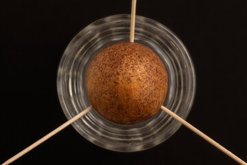 Growing avocado from the stone. The avocado pit on toothpicks in a glass of water. Top view.