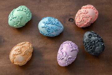 Six embossed carved vintage Easter eggs on a dark wooden background. Easter background with unusual Art Nouveau style Easter eggs on the side and space for text on the right. Top view.