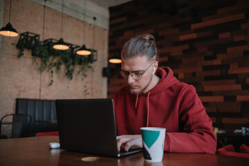 Portrait of happy male freelancer in optical eyewear for vision correction smiling at camera during break from web working online, cheerful hipster blogger sitting in cafe with mockup laptop