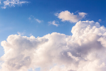 white cumulus clouds on a blue sky. beautiful nature background in evening light