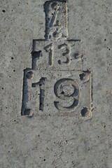 numbers 4, 13, 19 pressed into reinforced concrete