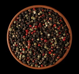 Colorful mixed pepper grains in clay pot isolated on black