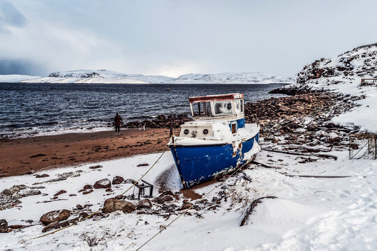 Old ship moored by the sea with the mountains in the background