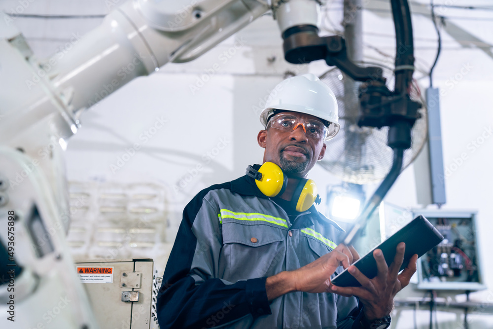 Poster african american factory worker working with adept robotic arm in a workshop . industry robot progra