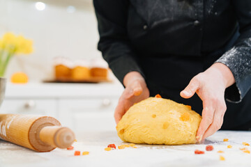 women's hands knead dough with candied fruits for easter cakes 