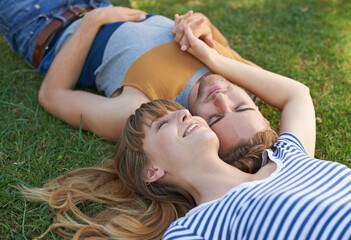 Happy and in love. Shot of a happy young couple lying in the park.