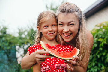 happy mother and daughter eating watermelon and having fun outdoor in summer day - Powered by Adobe