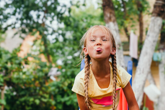 portrait of funny little girl with pigtails sticking her tongue out. Summer time