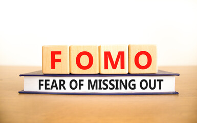 FOMO fear of missing out symbol. Concept words FOMO fear of missing out on wooden cubes on book on...