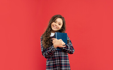 cheerful teen girl holding book on red background, childhood