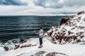 A man standing on a mountain and looking at the sea with dramatic clouds