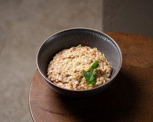 Buckwheat porridge in bowl with cheese on wooden background. Gluten free ancient grain for healthy diet. Top view. Copy space.
