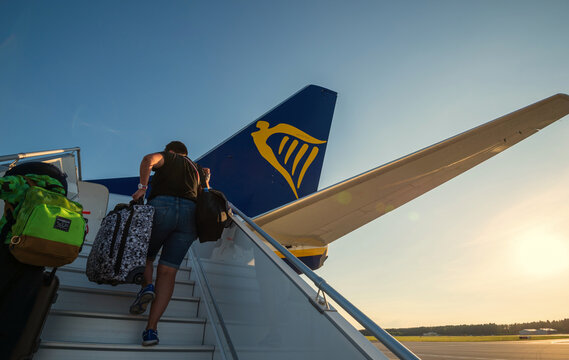 13/09/2021. Olsztyn-Mazury Airport, Poland. Ryanair airplane ready for departure. Passengers with suitcases on airport tarmac heading towards plane for boarding.
