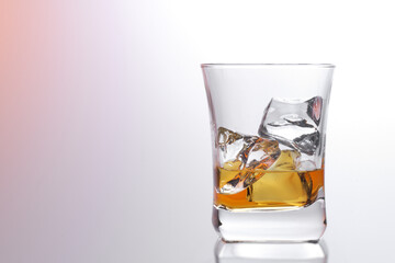 Glass of amber scotch whiskey and ice on a bright background