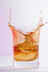 Glass of old whiskey with ice. A splashing glass of whiskey with ice isolated on a bright background