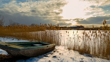 Heavenly winter clouds above a abandoned rural boat on lake
