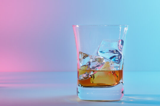 Glass of amber scotch whiskey and ice on a bright background
