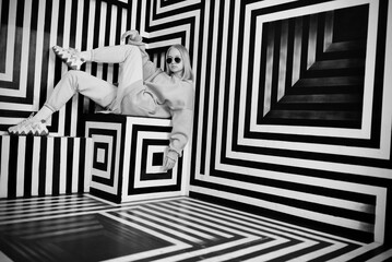 Portrait stylish girl sit in a black and white room with stripes.