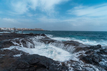 Waves beating in two holes formed in the rocks . Impressive rock formation in Telde. Gran Canaria