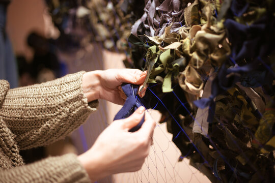 Women's hands weave a military camouflage net. Ukrainian women volunteers. High quality photo