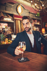 Relaxing with his favourite drink. Cropped shot of a young man sitting in a bar.