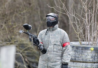 paintball player in a protective clothing aiming his gun at the enemy