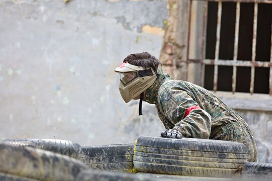 paintball player in a protective clothing hiding behind the fortifications and observing his enemies