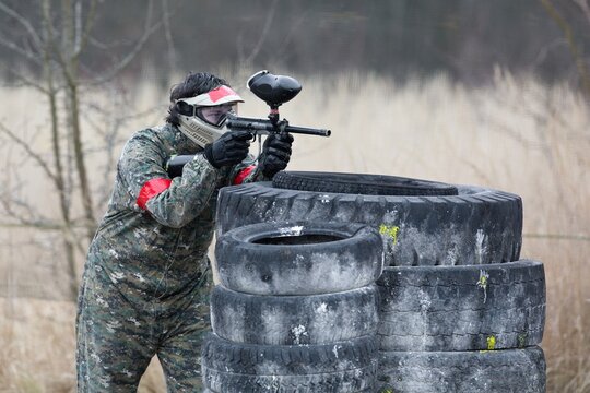 paintball player in a protective clothing aiming his gun at the enemy