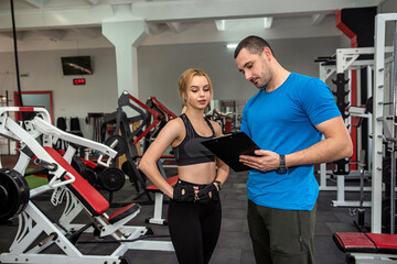 Fitness male trainer with his woman client working exercising at the gym