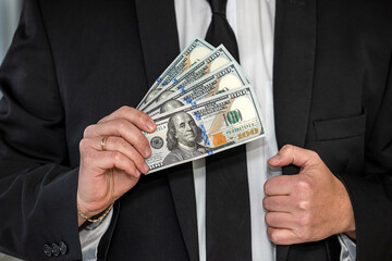 Young man in suit putting dollar bills in his pocket