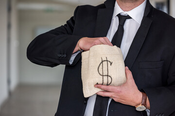 A middle-aged man in a business shirt holds a bag of dollars with an angry face.