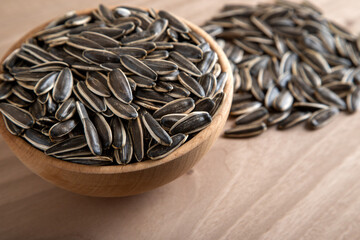 Black sunflower seeds in a bowl on wooden background	