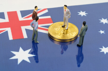 On the surface with the image of the flag of Australia are bitcoins and miniature figurines of...