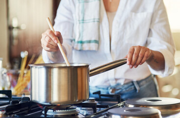 Dinner is almost ready. Cropped shot of a young woman stirring a pot in her kitchen at home.