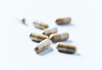 Gotu Kola (Centella Asiatica) capsules. Concept for a healthy dietary supplementation. Bright paper background. Soft focus. Close up.