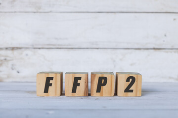 FFP2 concept written on wooden cubes or blocks, on white wooden background.