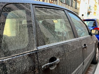 Car in Colmar, France covered with windblown Sahara sand and dust. Side view. 