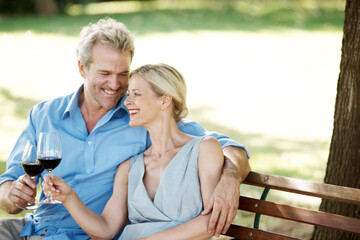 Taking some time out together. Happy mature couple toasting their love with two glasses of wine while outdoors.