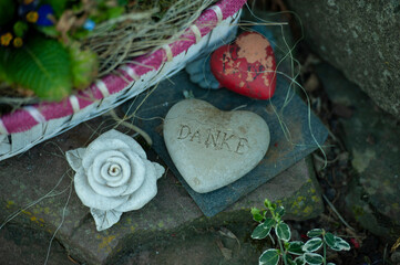 Flower on the grave, White stone heart with german text on the tomb. heart-shaped stone with text...