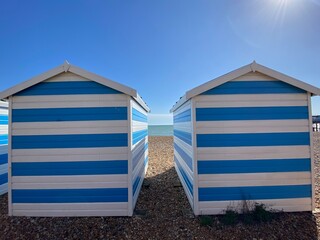 Hastings, East Sussex, UK -03.15.2022: Hastings seafront beach huts on summer day beautiful blue white striped huts on pebble beach