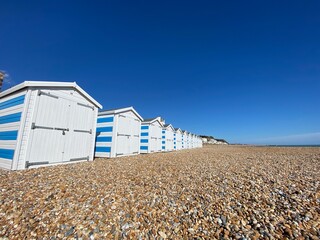 Hastings, East Sussex, UK -03.15.2022: Hastings seafront beach huts on summer day beautiful blue white striped huts on pebble beach