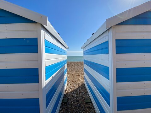 Hastings, East Sussex, UK -03.15.2022: Hastings seafront beach huts on summer day beautiful blue white striped huts on pebble beach