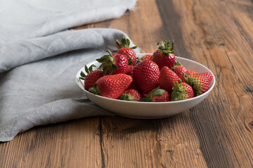 fresh sweet ripe strawberries in a bowl on a wooden table
