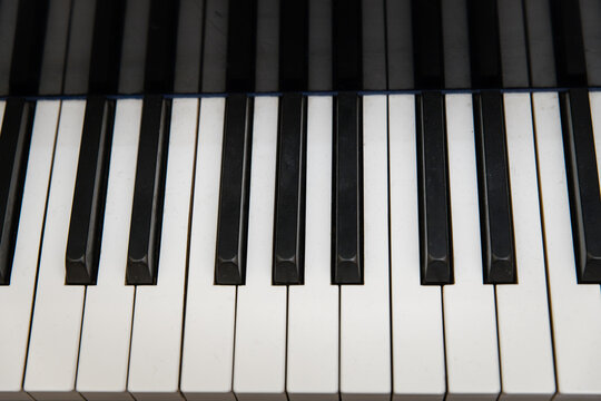 Closeup black and white grand piano piano keys shot from above.  