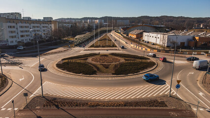A street with a roundabout and apartment blocks on a sunny day in Gdańsk.