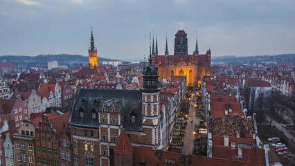 Obraz premium Old residential buildings, Mariacka Street and St. Mary's Church at the Main Town in Gdansk, Poland, aerial view at dusk.
