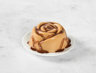 Coffee Panna Cotta with chocolate sauce, in the shape of a rose, on a plate. Light background